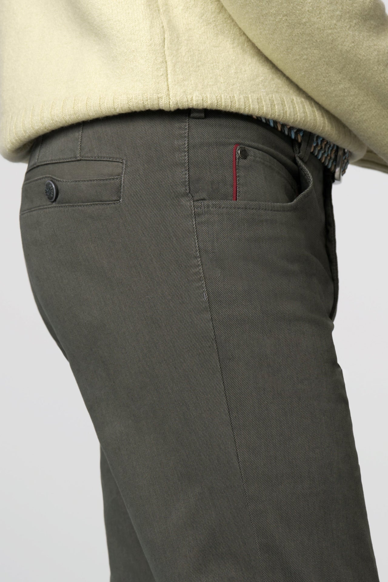 Dark gray pants with a beige sweater on a light gray background