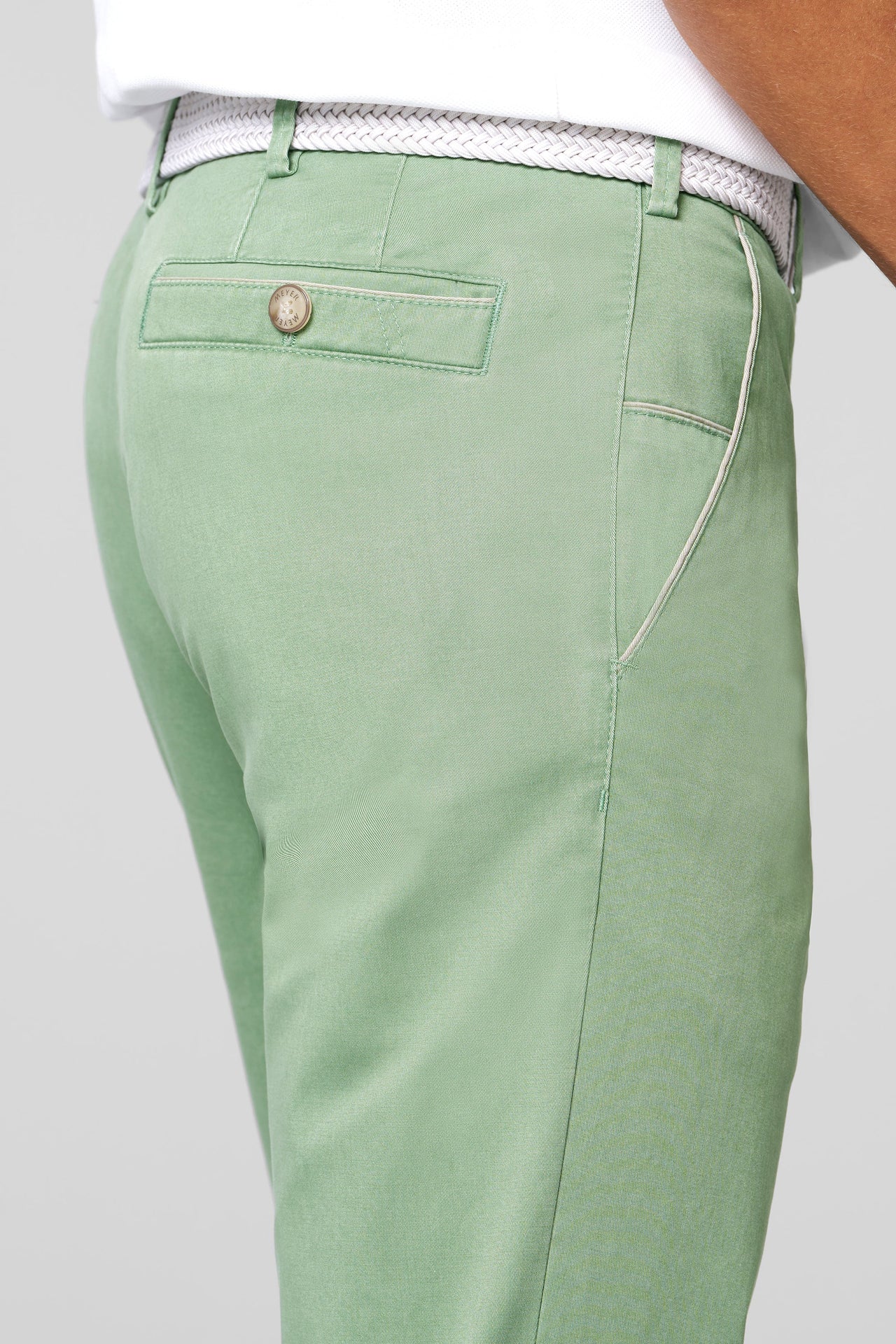 Green pants with a button on a light gray background